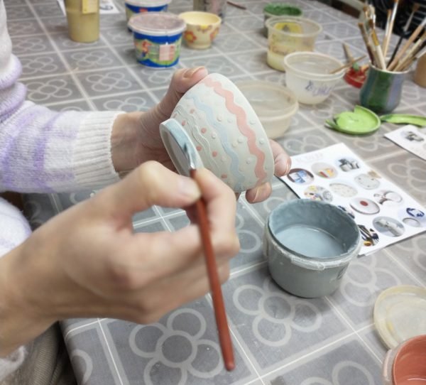 Persona pintando taza de cerámica a mano.