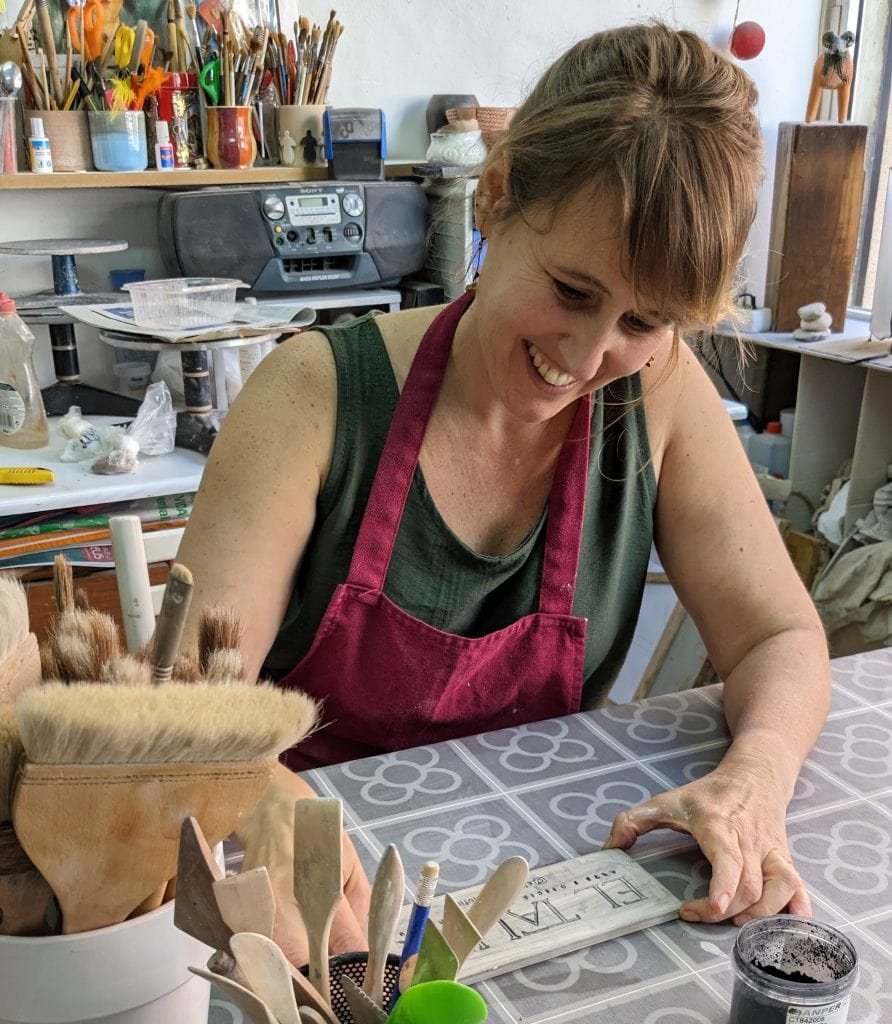 Mujer sonriente trabajando en taller de cerámica.